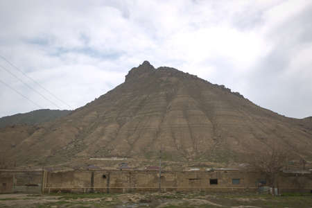 view of volcano . bare mountain and country houses in front . There are rocks at the top of the mountainの写真素材