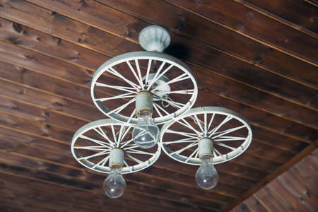 Modern Hanging Lamp Art And Science. Old vintage lighting decor. Lights made of white iron horse-drawn carriage . group of hanging lights in coffee shop with shallow depth of field, interior design .の写真素材