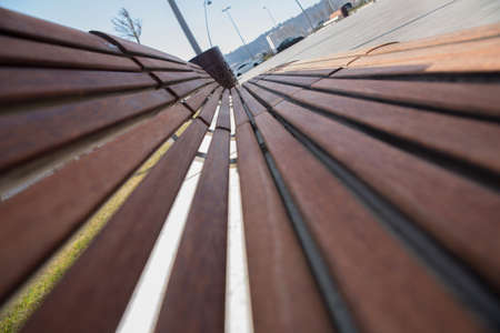 Empty Park wooden bench Closeup view. Wood exterior material. Wood material details. Blank Old bench in a shady area of the garden or the park,outdoor. Shaded wood park bench surrounded by greeneryの写真素材
