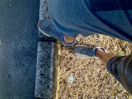 a pair of feet using shoes on the side of the road photo