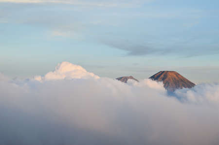 two mountain peaks visible behind the clouds photo