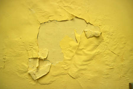 yellow wall with peeling paint photoの写真素材