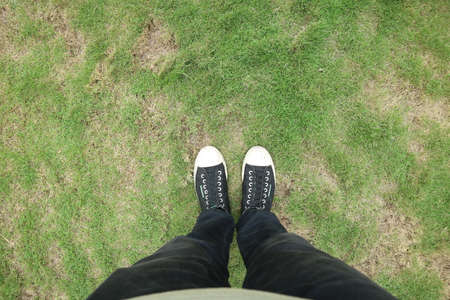 man's feet standing on green grass photo