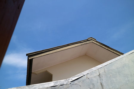 a photo of a view of a house roof and walls with a view of the bright blue sky
