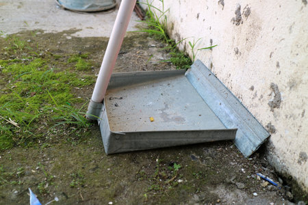 Photo of a dustpan made of zinc or light steel sheet, is outside the house.