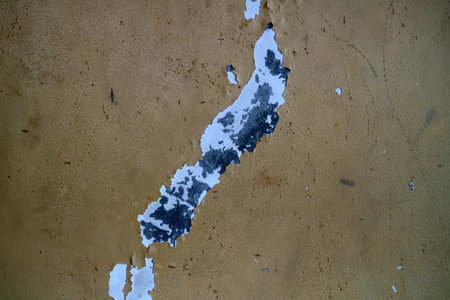 A close up view of a textured wall with peeling paint, revealing layers of color underneath. The...