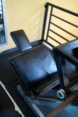 A close up view of a black padded exercise bench in a gym setting, featuring metal framing and a...