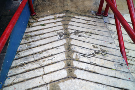 Concrete ramp with red railings and textured surface for accessibility.の写真素材