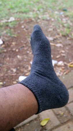 Close up of a persons foot wearing a dark gray sock outdoors.の写真素材