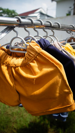 Colorful childrens shorts hanging on a clothesline outdoors.