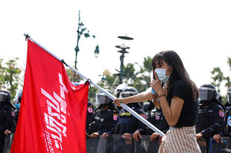 Bangkok, THAILAND - March 30, 2021: Pro-democracy protesters wave the flag at front of police line during protests at front government house after crackdown Talu Fah Village on March 28.のeditorial素材