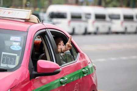 Bangkok, THAILAND - April 10, 2021: Woman in taxi a three finger salute to show symbolic gestures to...
