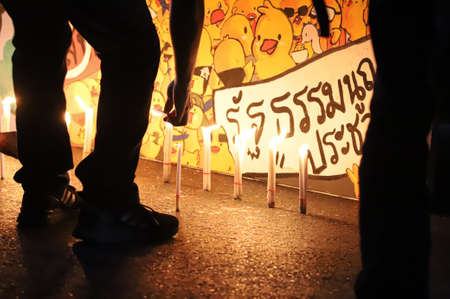 Bangkok, THAILAND - June 24, 2021: Pro-democracy protesters light a candle to memorial Siamese revolution of 1932 in the dawn at Democracy Monument.のeditorial素材