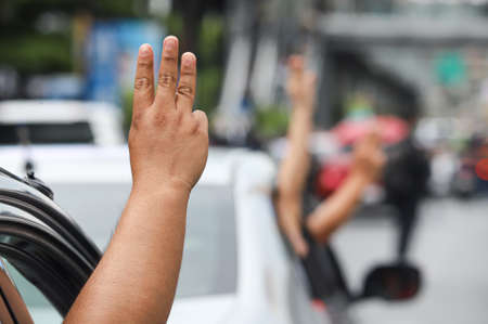 Bangkok, THAILAND - July 10, 2021: "Car Mob" Protesters a three finger salute to show symbolic gestures between driving vehicles and honk for protest and dissatisfaction the government under PM Prayut.のeditorial素材