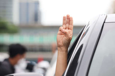 Bangkok, THAILAND - July 10, 2021: "Car Mob" Protesters a three finger salute to show symbolic gestures between driving vehicles and honk for protest and dissatisfaction the government under PM Prayut.のeditorial素材