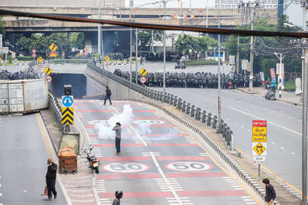 Bangkok, THAILAND - August 7, 2021: Riot police block road to 1st Infantry Regiment by container and crack down protesters by tear gas, rubber bullets, water cannon.のeditorial素材