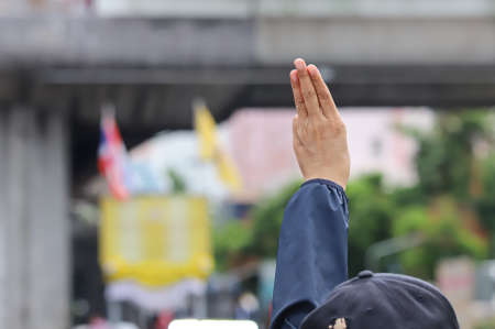 Bangkok, THAILAND - August 7, 2021: Protesters a three finger salute to show symbolic gestures between gather at Victory Monument and walk to the 1st Infantry Regiment, PM Prayut's house.のeditorial素材