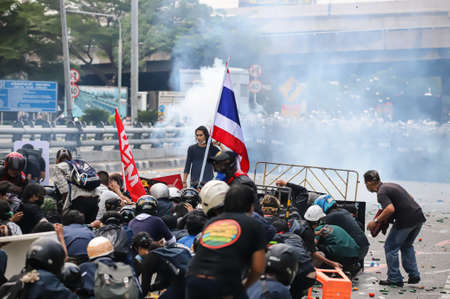 Bangkok, THAILAND - August 7, 2021: Riot police block road to 1st Infantry Regiment by container and crackdown protesters by tear gas, rubber bullets, water cannon.のeditorial素材