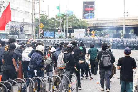Bangkok, THAILAND - August 7, 2021: Riot police block road to 1st Infantry Regiment by container and crackdown protesters by tear gas, rubber bullets, water cannon.のeditorial素材