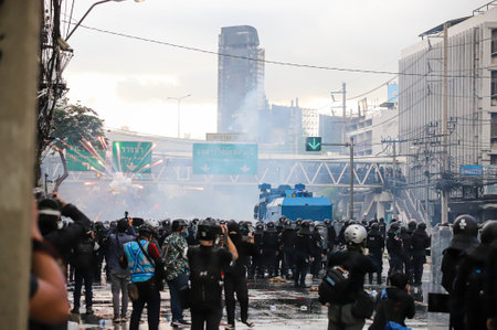 Bangkok, THAILAND - August 7, 2021: Riot police block road to 1st Infantry Regiment by container and crackdown protesters by tear gas, rubber bullets, water cannon.のeditorial素材