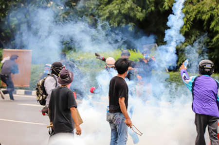 Bangkok, THAILAND - August 13, 2021: Riot police crackdown by tear gas and rubber bullets after protesters try to pass barrier to 1st Infantry Regiment for protest about failed covid-19 management.のeditorial素材
