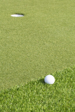 A golf ball near the hole on a green の写真素材