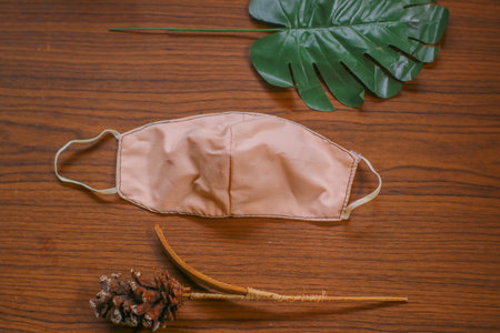Modern Handmade cotton cloth face mask protective against dust and virus top view. Coronavirus preventive cotton mask. Homemade face mask. DIY concept. Face shield mask on wooden backgroundの写真素材