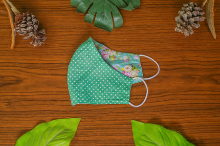 Modern Handmade cotton cloth face mask protective against dust and virus top view. Coronavirus preventive cotton mask. Homemade face mask. DIY concept. Face shield mask on wooden backgroundの写真素材