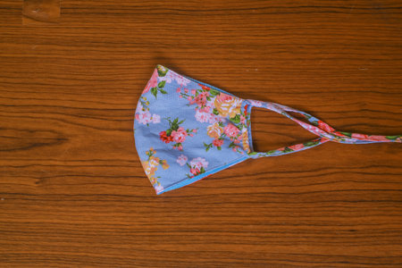 Modern Handmade cotton cloth face mask protective against dust and virus top view. Coronavirus preventive cotton mask. Homemade face mask. DIY concept. Face shield mask on wooden backgroundの写真素材