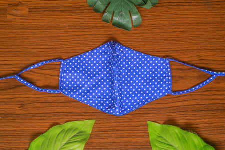 Modern Handmade cotton cloth face mask protective against dust and virus top view. Coronavirus preventive cotton mask. Homemade face mask. DIY concept. Face shield mask on wooden backgroundの写真素材