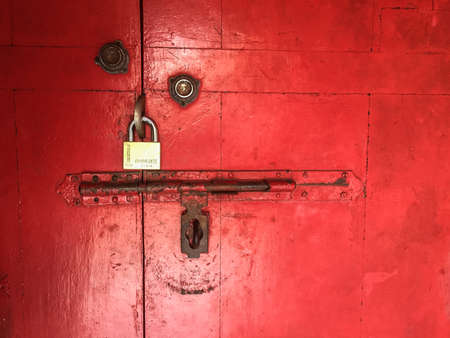 Red, rustic door with closed padlockの写真素材