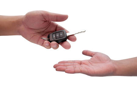 Male hand holding a car key and handing it over to another person isolated,の写真素材
