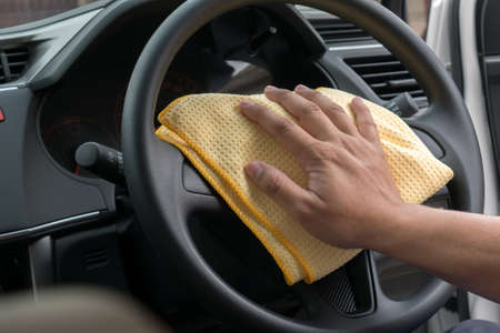 Hand cleaning car steering wheel with microfiber cloth, auto detailing (valeting) conceptの写真素材