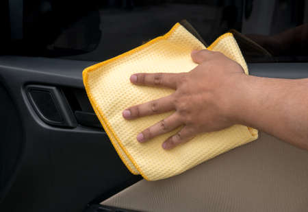 Hand cleaning interior car door panel with microfiber cloth