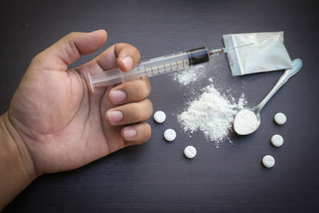 drug addict hand / drugs narcotic syringe on floorの写真素材