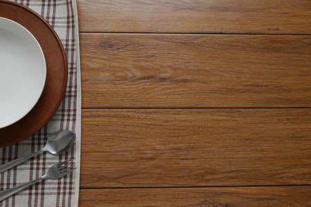 white plate and fork on old wooden table with  checked tablecloth and copyspace, top viewの写真素材