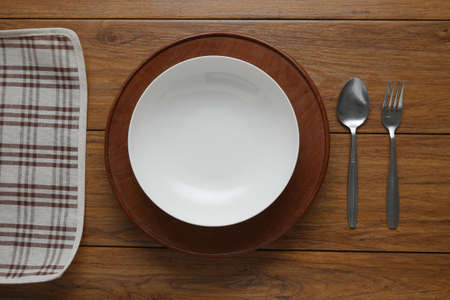 white plate and fork on old wooden table with  checked tablecloth and copyspace, top view