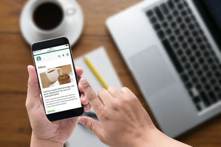 Bangkok, Thailand - Feb 5, 2015 : A man hand holding iphone with Starbucks menu web page on screen, coffeeのeditorial素材