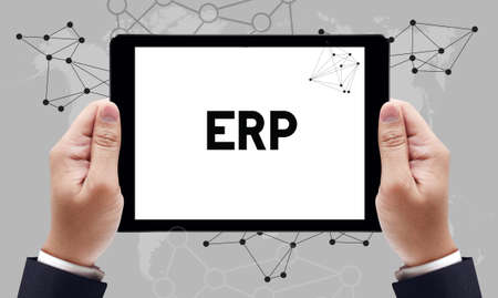ERP text on the tablet pc screen held by businessman hands - online concept, top viewの写真素材
