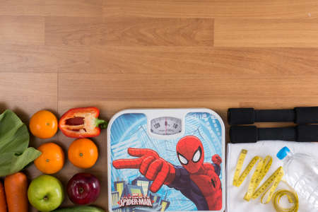 Fitness and weight loss concept, dumbbells, white scale, towel, fruit and mobile phone on a wooden table, top view, free copy spaceの写真素材