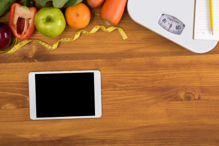 top view, digital tablet on a wooden table,  fitness and weight loss concept, dumbbells, white scale, towels, fruit, Weight lossの写真素材