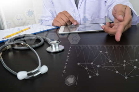 top view of Medicine doctor hand working with modern computer and digital  tablet with digital medical diagram on wooden desk as medical conceptの写真素材