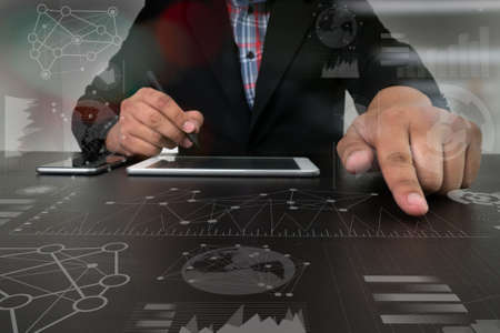 business man hand working on digital tablet computer with digital layer business strategy and social media diagram on wooden deskの写真素材