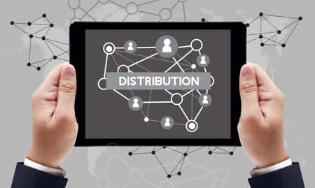 DISTRIBUTION text on the tablet pc screen held by businessman hands - online concept, top viewの写真素材