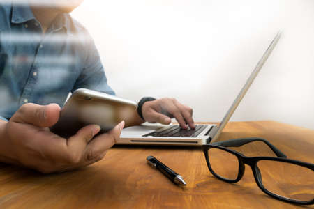 business documents on office table with smart phone and digital tablet and graph business diagram and man working in the backgroundの写真素材