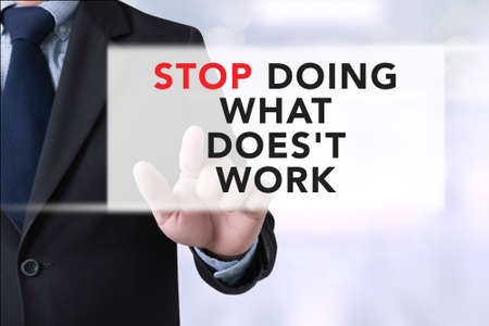 STOP DOING WHAT DOES'T WORK, Businessman touching a touch screen on blurred city backgroundの写真素材