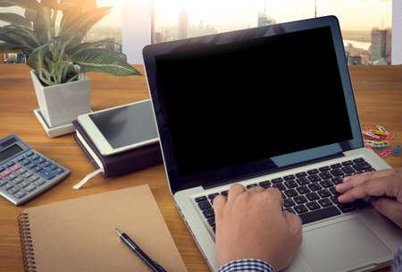 Close up of business man hand working on blank screen laptop computer on wooden desk as concept,...
