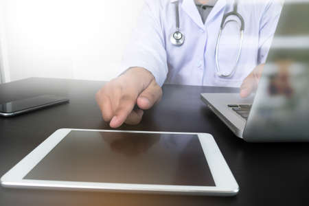 Medicine doctor hand working with modern computer and digital pro tablet on wooden desk as medical...