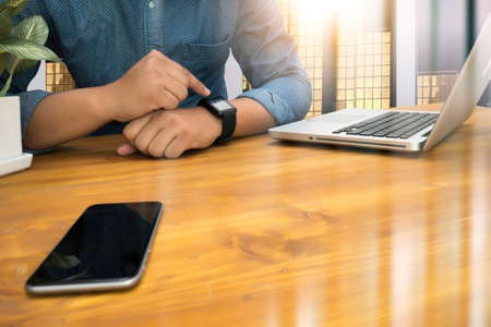 Cropped shot Silhouette of a man's hands using a laptop, business man hands busy using laptop at office desk, typing on computer sitting wooden table, phone on table, filter sun, copy spaceの写真素材