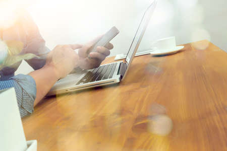 designer hand working and smart phone and laptop on wooden desk in officeの写真素材